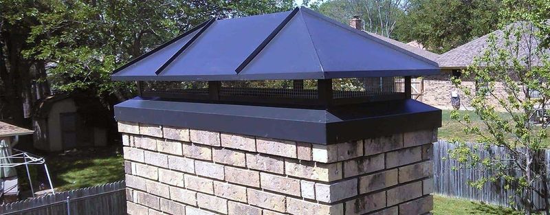 A black hip-roof cap on a brick chimney
