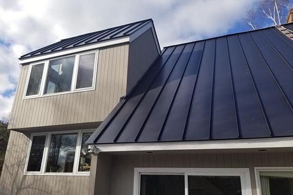 A black standing seam metal roof on a modern house