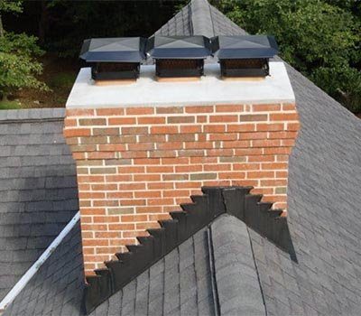 A brick chimney with a concrete crown and three black caps