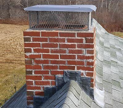 A brick chimney with a mesh cap and step flashing