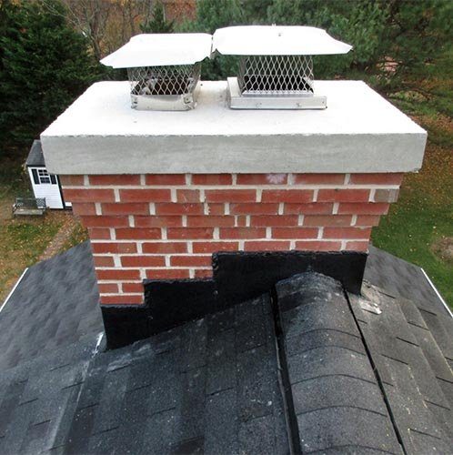 A brick chimney with a new crown and two flue caps