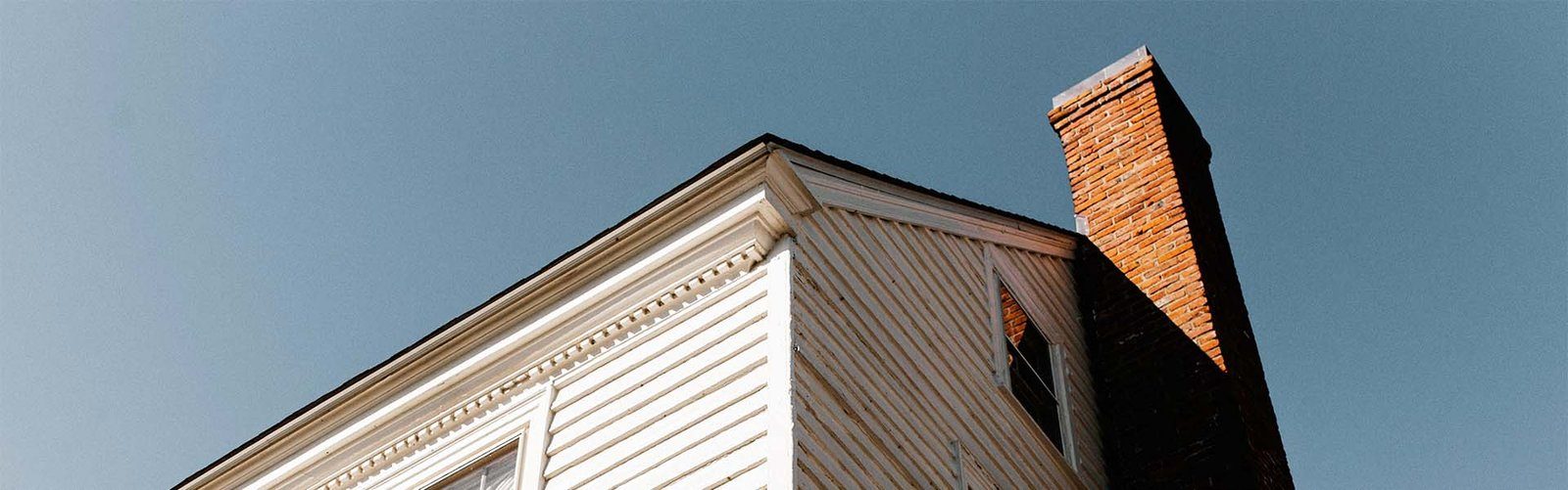 A brick chimney on a white clapboard house