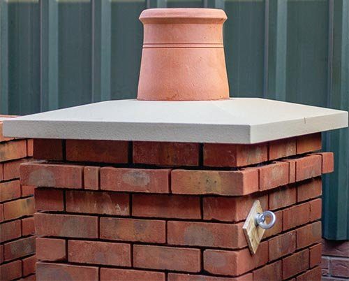 A clay chimney pot on a brick chimney with a concrete crown