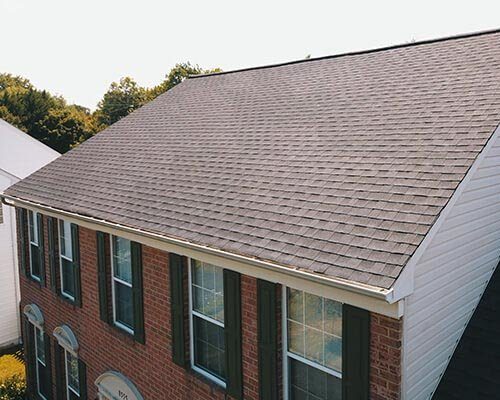 A brown shingle roof on a brick colonial house