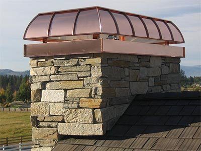A barrel-shaped copper cap on a stone chimney