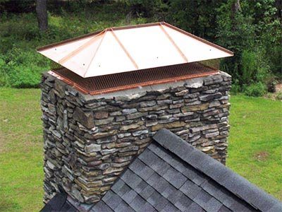 A copper cap on a stacked-stone chimney