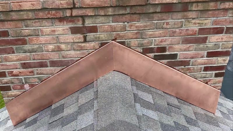 New copper flashing where a brick chimney meets the shingles