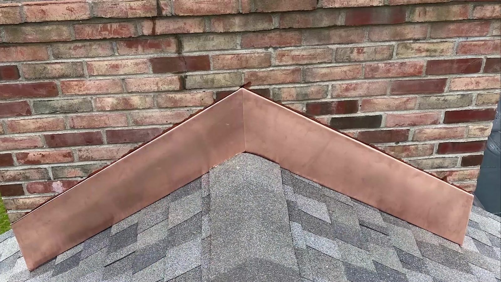 New copper flashing where a brick chimney meets the shingles
