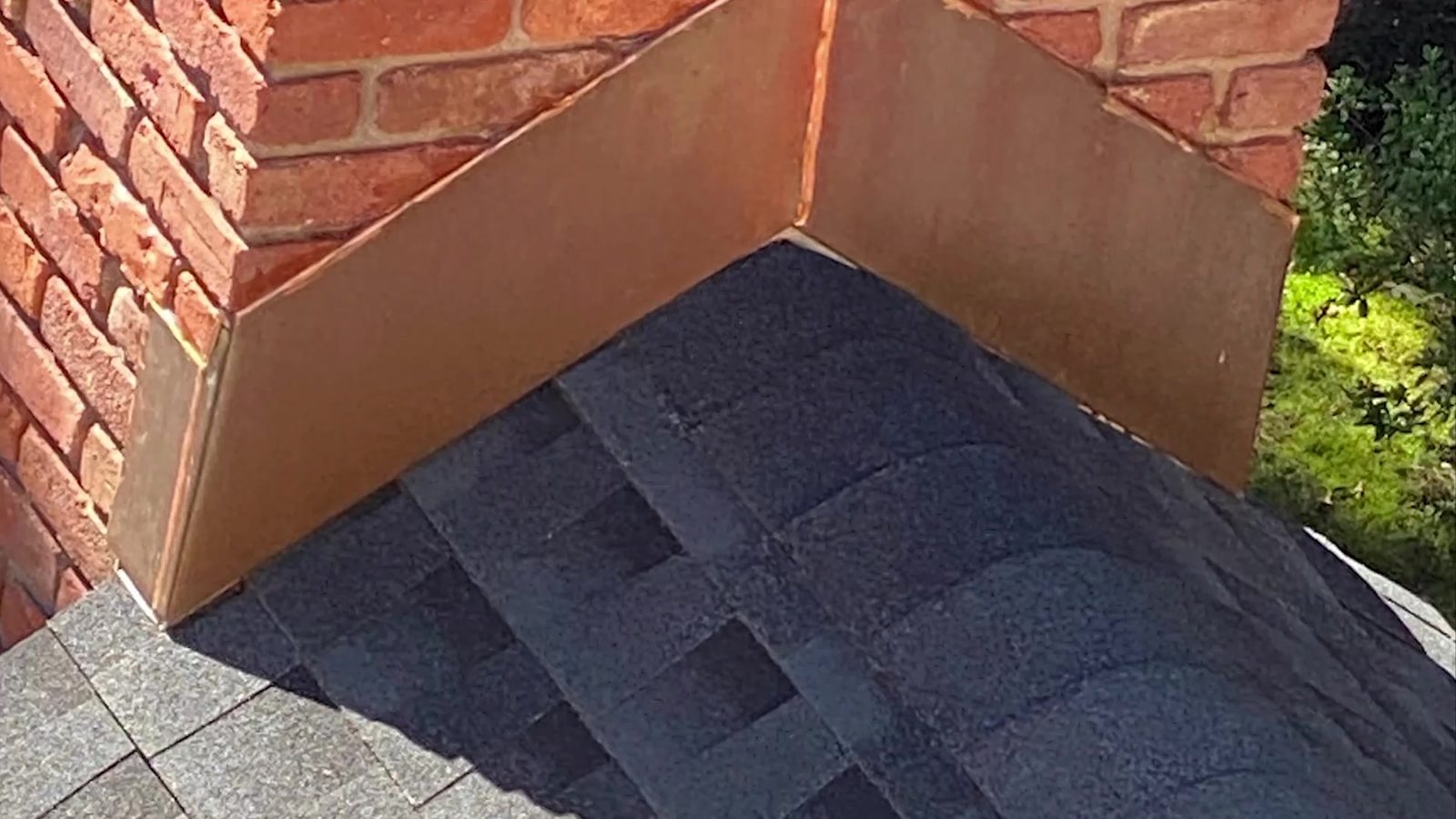 New copper flashing at the corner of a brick chimney