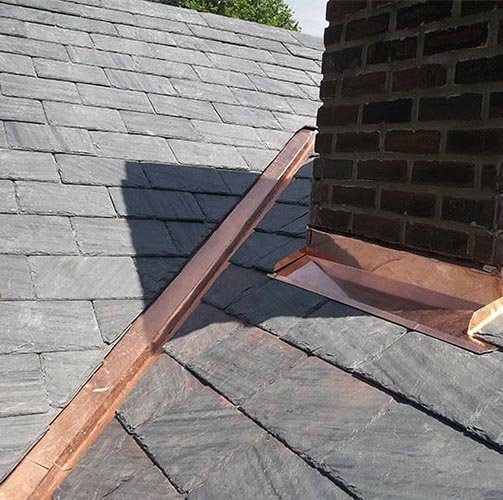 Copper flashing where a chimney meets a slate roof