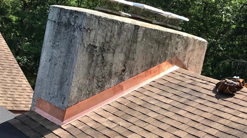 New copper flashing around the base of a stucco chimney
