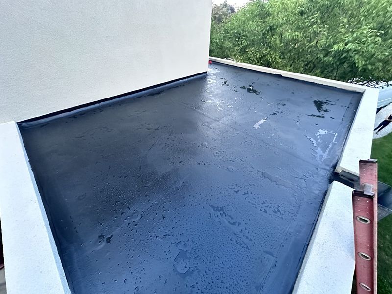 A new flat roof after rain, with white parapet walls around it