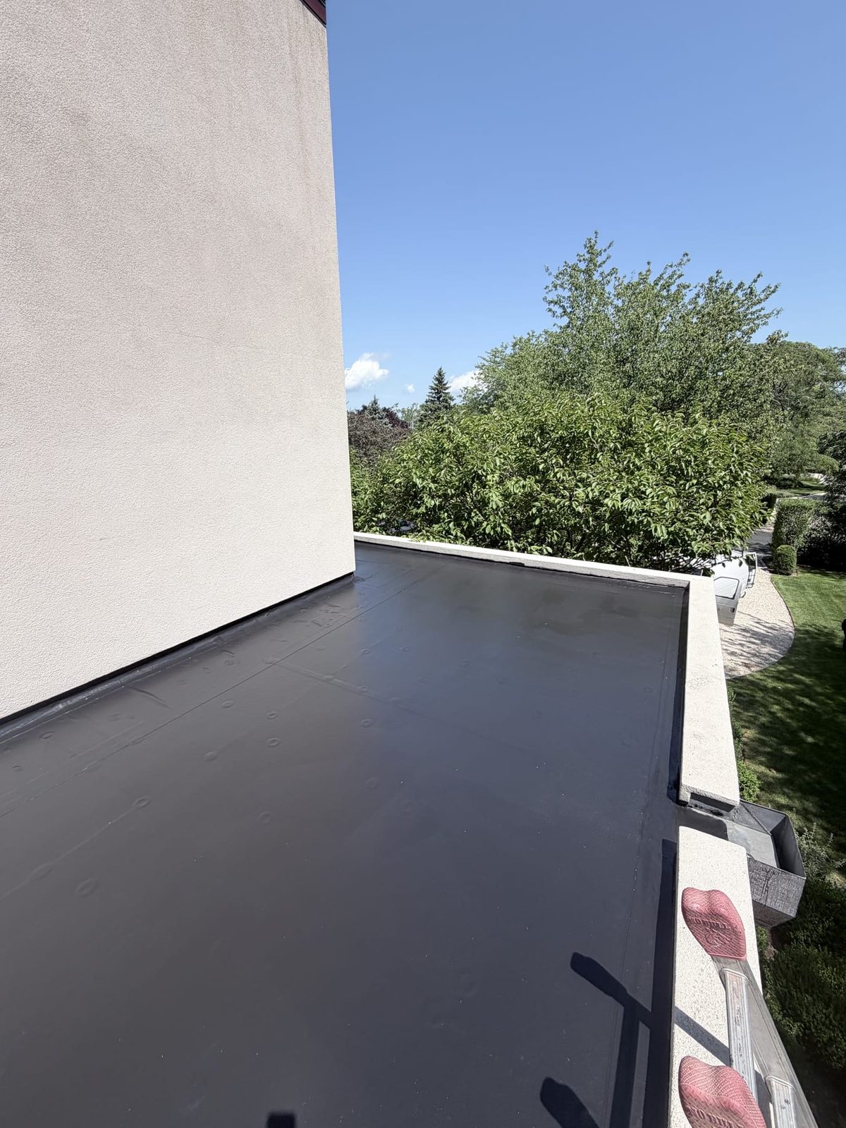 A new black flat roof membrane against a white stucco wall