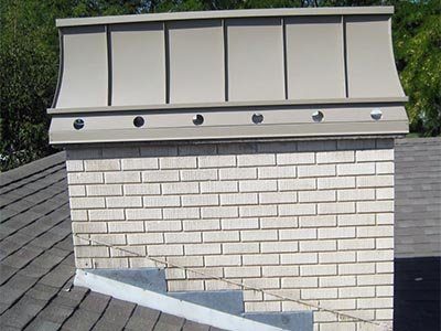 A grey metal shroud on a white brick chimney