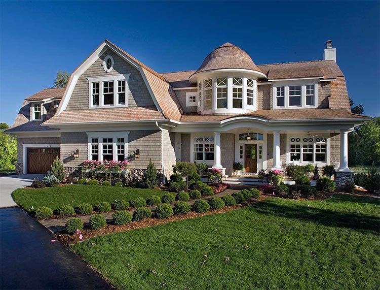 A Hamptons-style house with a cedar roof and a round bay