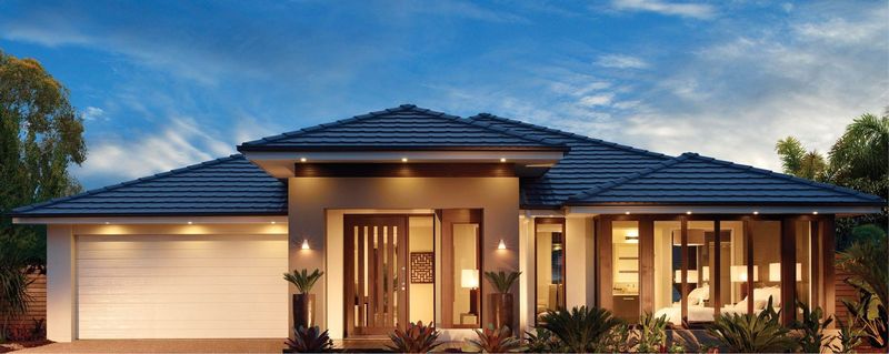 A single-story house with a dark hip roof, lit up at dusk