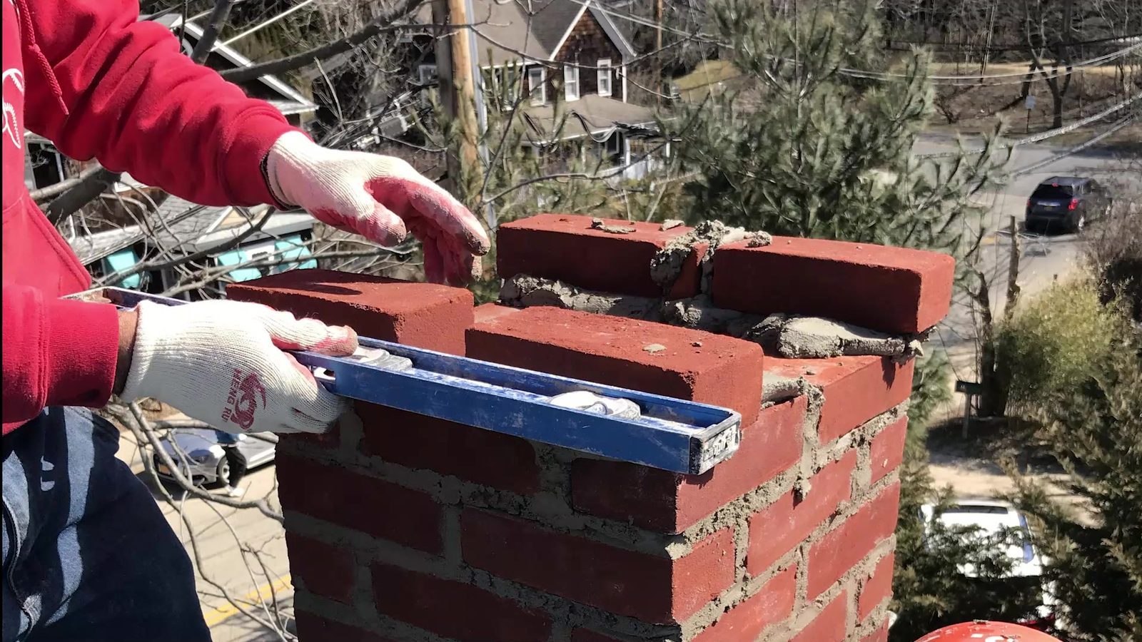 Laying brick on a chimney rebuild, checked with a level