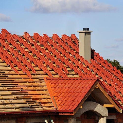 An orange tile-profile roof with a small chimney