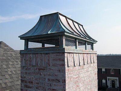 A patinated copper cap on a brick chimney