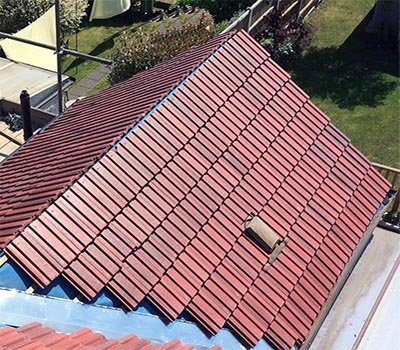 Red metal shingles being installed over underlayment