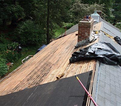 An old roof being torn off around a chimney