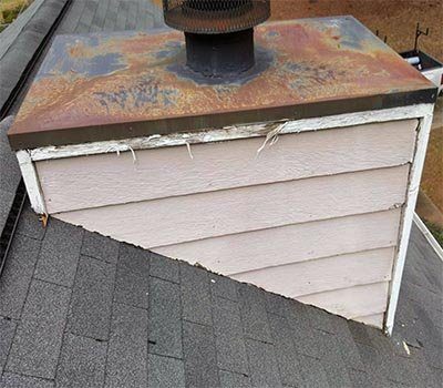 A rusted chase cover on a sided chimney chase