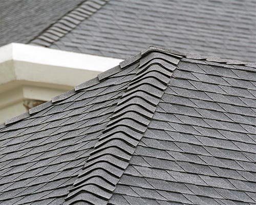 Ridge shingles along the hip of a grey shingle roof