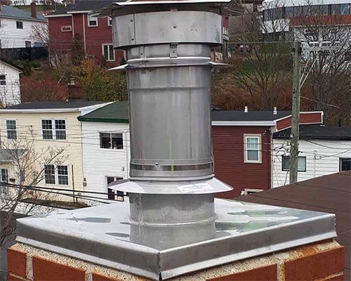 A stainless steel flue pipe and cap on a brick chimney