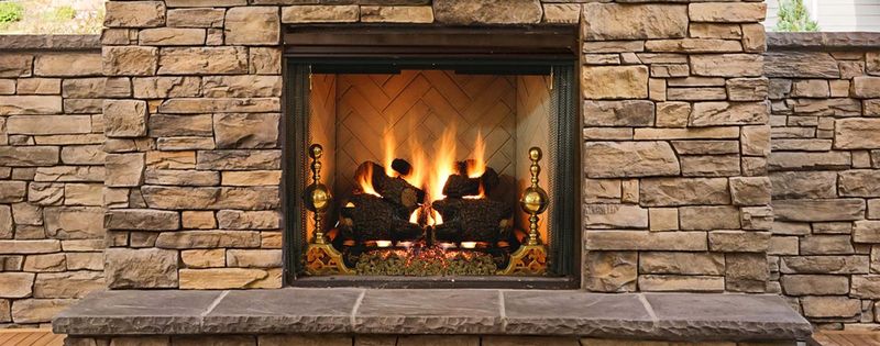A stacked-stone fireplace with a fire burning