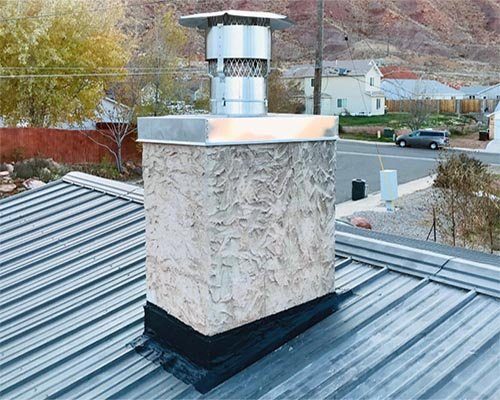 A stucco chimney chase with a new metal chase cover