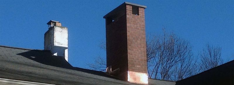 A white chimney and a brick chimney on one roof