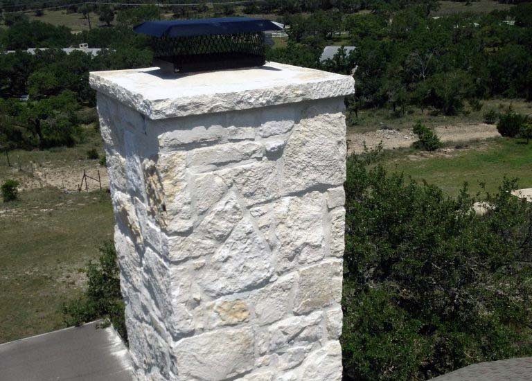 A white stone chimney with a black cap
