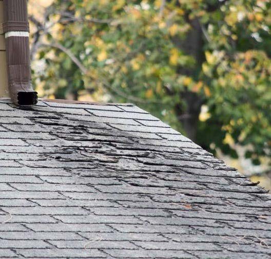 Worn, cracked shingles below a vent pipe